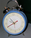A photograph of an old-fashioned wind up alarm clock with bells on top of it