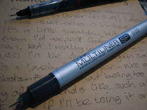 = A photograph of two fine point pens laying on a piece of paper with handwriting on it 