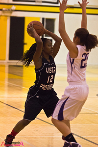 A photograph of two female high school basketball players on the court during a game