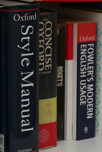 A photograph of writing resource books; a style manual, a dictionary, a thesaurus, and a book on modern English usage.