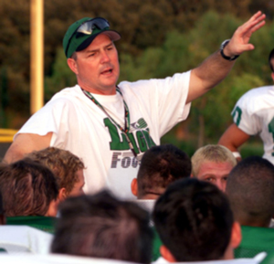A photograph of a football coach talking to his team