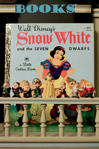 A cover of a vintage children's book “Snow White and the Seven Dwarfs.” In front of the book are small figurines of the dwarfs featured in the book.