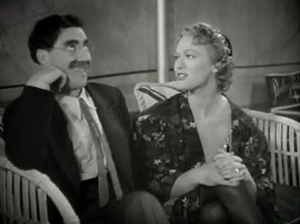A photograph of comedian/actor Groucho Marx seated on a couch with actress Eve Arden