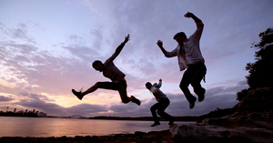 A photograph of three young men jumping into the air simultaneously.
