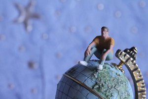 A photograph of a male figurine sitting on top of the world.