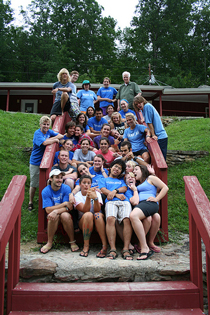 A photograph of a large group of camp counselors posing on a hillside.