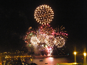 A photograph of a night time fireworks display over water
