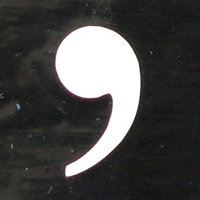 A graphic image of a comma by itself on a dark background.