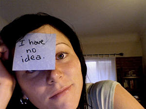 A photograph of a young woman with a Post-It note on her forehead that reads 'I have no idea'