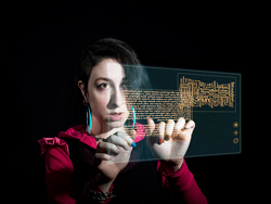 In an image out of a science fiction movie, a woman interacts with a floating, transparent computer screen. Her bright clothing, pale face, and the floating computer screen are stark against a black background.