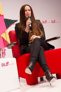 A photograph of musician/songwriter Alanis Morissette seated and speaking into a microphone