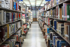 photo of a long row of shelves full of books in a library