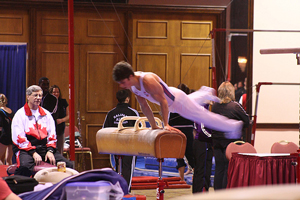 photo of a male gymnast practicing a routine on a pommel horse