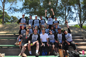 An amateur softball team cheers at the camera. The team is made up of both women and men.