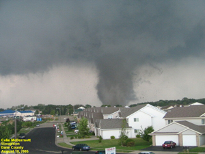 A photograph of a tornado touching down at the edge of a housing development