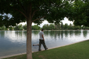 photo of a young man walking on the edge of park lake