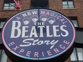 A photograph of a sign that reads: A New Magical Experience: The Beatles Story. It also features images of the Beatles faces.