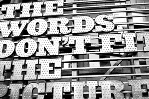 A photograph of a sign with part of the words outside of the frame. It reads: The words don't fit the picture.