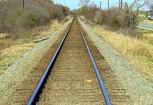 photo of train tracks in rural area; a farm road runs along one side about 20 or 30 yards