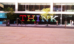 A photograph of a large sign outside of a building lobby. The sign reads “THINK”.