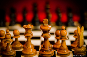 A photograph of a chess board taken at eye level behind the King and Queen.