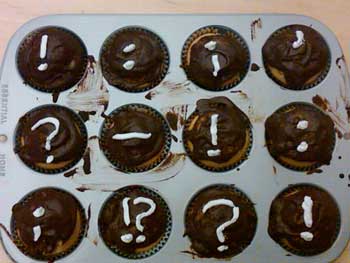 A photograph of a tray of cupcakes with various punctuation marks on them