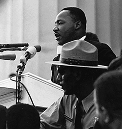 Martin Luther King Jr. speaking with an arm upheld in a gesture of exhortation.