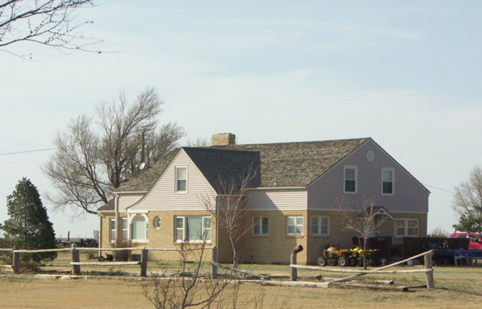 A large home surrounded by a fence in disrepair.