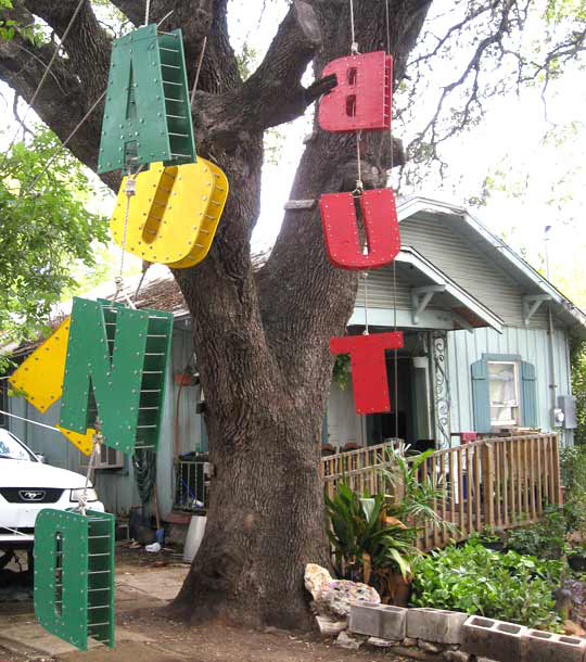 Image of the words “And” and ”But”, conjunctions, hang from a tree in Austin, TX.