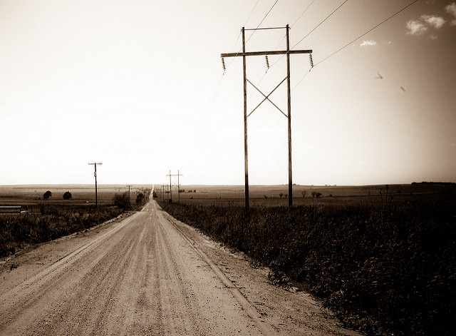 A wide dirt road stretches through the countryside