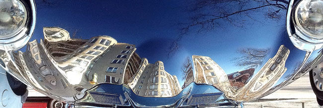 Buildings reflecting off the hood of a car. 