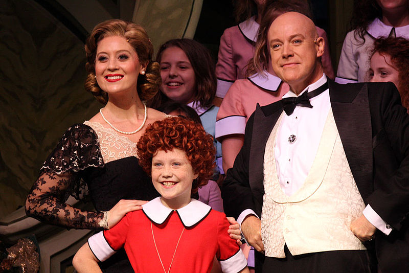 Scene from the musical Annie with Annie and Daddy Warbucks and cast