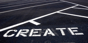 A photograph of the word 'create' painted in a parking lot