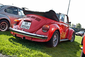 A photograph of a convertible Volkswagen Bug from the rear