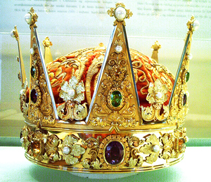 A photograph of a crown; It is covered with intricate patterns an jewels.