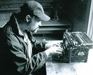 A photograph of a man typing on an an antique typewriter.
