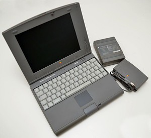 A photograph of a Macintosh Power Book laptop with the accessories.
