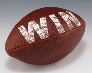 A photograph of an American football with the word 'WIN' painted on it