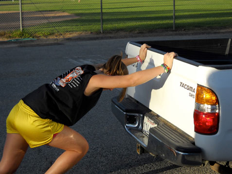 Image if of a girl trying to push a truck