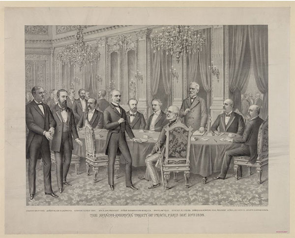Image of an original print of the meeting of 12 men who signed the peace treaty. Four of the men are standing while six are seated at a long table.
