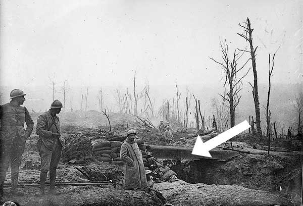 Image of a trench with several soldiers underneath, while other soldiers stand around the perimeter. 
