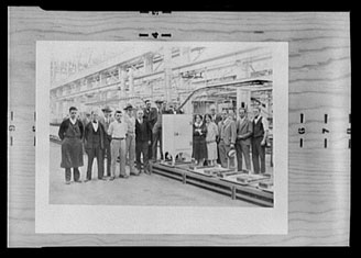 Image of a group of men and women standing near a refrigerator