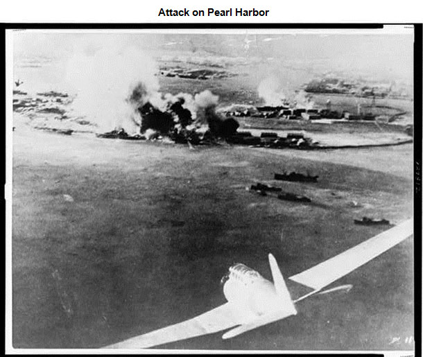 Image of a Japanese plane as it approaches Pearl Harbor. There are plumes of smoke that are coming from the ground