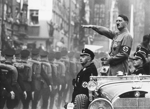 A photograph of Adolf Hitler and Heinrich Himmler reviewing SS troops at a parade in Nuremberg, Germany. Everyone present is wearing some variant of a Nazi uniform with swastika arm bands.