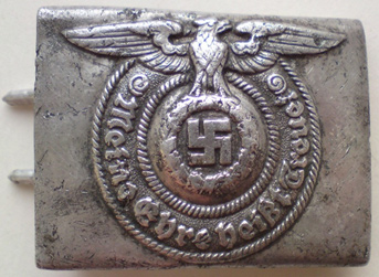 An SS uniform belt buckle. It has an eagle with its wings outstretched grasping a swastika in its talons. Surrounding the eagle is an inscription reading 