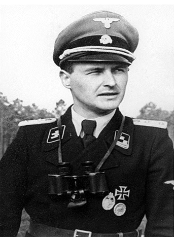 A photograph of an SS officer in his black uniform with SS collar patches, German medals, and a cap with the Totenkopf, or Death's Head emblem on it.