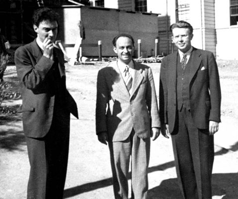 A photograph of atomic scientists Robert Oppenheimer, Enrico Fermi, and Ernest Lawrence standing outside. They are all wearing suits.