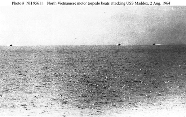 Image of an ocean with three small boats approaching far off in the distance. The photo is taken from the USS Maddox.