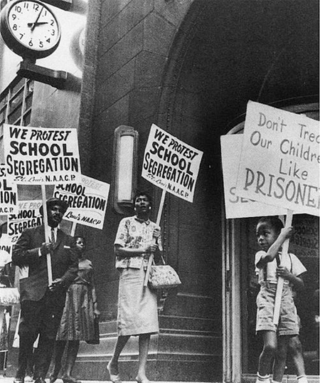 A photograph of a an African American family protesting school segregation carrying signs saying 