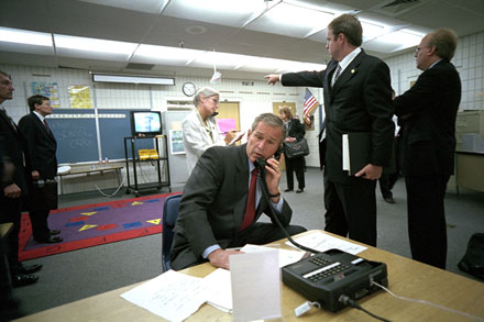 Director of Communications Dan Bartlett points to news footage of the World Trade Center Towers burning, September 11, 2001, as President George W. Bush gathers information about the attack from Emma E. Booker Elementary School in Sarasota, Florida